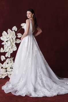 a woman in a wedding dress standing next to flowers