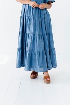 Features Sweetheart neck Flutter sleeves Tiered skirt with floral embroidered detail Smocked back Elastic waist Dusty blue color Pockets Self: 100% Cotton; Lining: 100% Polyester Size + Fit Small 0-4, Medium 4-8, Large 8-12, XL 14-18 Kristin is 5'4", a size 1 and is wearing a Small Runs true to size. Measurements taken while laying flat and then doubled. They do no account for stretch. Click here for shoes Size Bra Band Length Small 34" 49" Medium 36" 49" Large 38" 50" X-Large 40" 50" Blue Tiered Skirt For Spring, Flowy Tiered Skirt Dress With Floral Embroidery, Blue Cotton Dress With Ruffled Skirt, Tiered Dress With Floral Embroidery, Blue Floral Embroidery Skirt For Spring, Blue Flowy Tiered Dress, Bohemian Blue Tiered Skirt Dress, Blue Bohemian Dress With Tiered Skirt, Blue Cotton Dress With Gathered Skirt