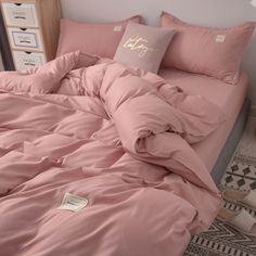 an unmade bed with pink sheets and pillows