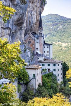 an old church built into the side of a cliff in europe, surrounded by trees and mountains