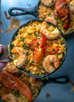 a person holding a skillet filled with shrimp and rice