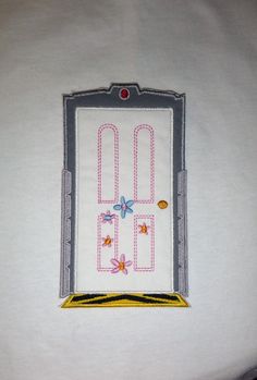 a white t - shirt with embroidered letters and flowers on the front, along with a yellow border