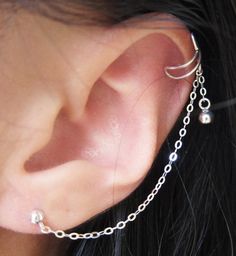 This sterling silver earring features a small dangle on an ear cuff that is connected to an earring stud with a chain forming this Sterling Silver Plain Ball Dangle Cuff Earring. This ear cuff requires no piercing so anyone with just one ear lobe piercing can wear this earring. The ear cuff is similar to a clip-on earring where it cuffs onto the ear but this goes onto the upper (helix or rim) cartilage or middle cartilage. Then squeeze the ear cuff to secure. This listing is for one cuff earring Elegant Sterling Silver Ear Cuff With Adjustable Chain, Silver Sterling Ear Cuff With Adjustable Chain, Silver Sterling Silver Cartilage Earrings With Adjustable Chain, Adjustable Dangle Sterling Silver Piercings, Silver Adjustable Ear Cuff With Chain, Adjustable Silver Ear Cuff With Chain, Minimalist Silver Ear Cuff With Adjustable Chain, Silver Dangle Ear Cuff With Matching Earrings, Adjustable Dangle Ear Cuff In Sterling Silver