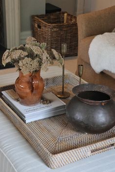 a coffee table with flowers in a vase and books on the tray next to it