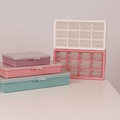 three plastic storage boxes sitting on top of a white table next to each other with dividers in them