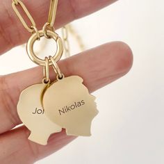 a hand holding a gold keychain with two charms that say, jol nikolas and nickolas