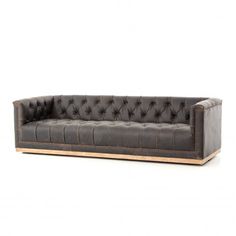 a black leather couch with wooden legs and buttons on the back, against a white background