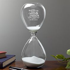 an hourglass sitting on top of a wooden table next to a pen and notebook