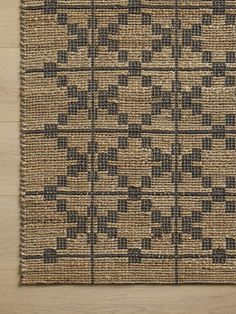 an area rug with black and tan designs on it, sitting on a wooden floor