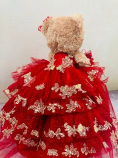 a teddy bear dressed in a red dress with gold sequins on the skirt