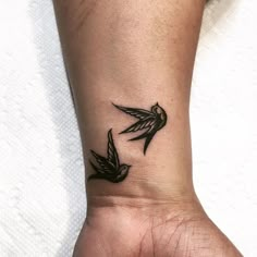 a small tattoo on the wrist of a woman with two birds flying above her arm