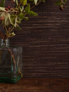 a vase filled with flowers sitting on top of a wooden table next to a wall