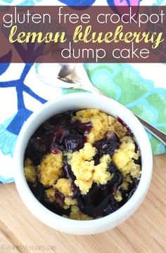 a bowl of lemon blueberry dump cake on a wooden table with a spoon in it