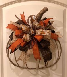 an orange and brown wreath hanging on the front door with burlocked ribbon