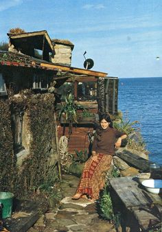 a woman sitting on the side of a building next to the ocean