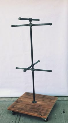 a wooden stand with four metal bars on it's top and two black poles in the middle