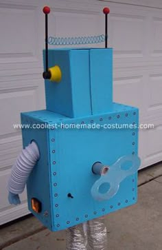 a blue robot made out of cardboard and some wires attached to the back of it