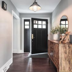 an entryway with a wooden cabinet and black doors