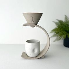 a white cup sitting on top of a saucer next to a potted plant