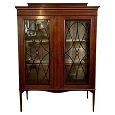 a wooden cabinet with glass doors on the top and bottom shelves, in front of a white background