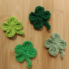 three crocheted shamrocks sitting on top of a wooden table