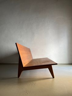 a wooden chair sitting on top of a floor next to a white wall in an empty room