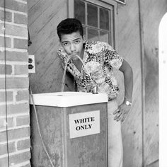 a man standing next to a trash can with his hand on his mouth and the words white only written on it