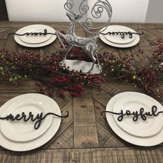 a wooden table topped with white plates covered in metal reindeer head and word merry joy