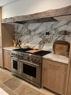 a kitchen with marble counter tops and stainless steel stove top ovens, cabinets, and drawers