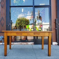 a wooden table sitting in front of a store window