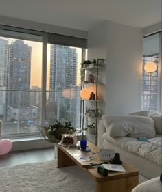 a living room filled with furniture and large windows overlooking the cityscape in the distance