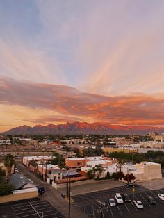 the sun is setting over a parking lot with mountains in the background