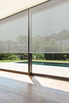 an open window with blinds on it in front of a swimming pool and garden area