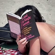 a woman laying on the ground reading a book