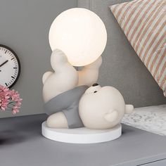 a white lamp sitting on top of a table next to a clock