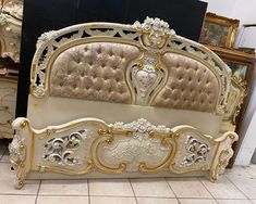 an ornate bed frame with gold and white paint on the headboard, along with other antique furniture