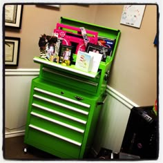 a green toolbox with many items on it sitting in front of a white wall