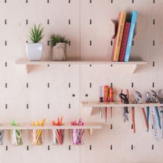 two wooden shelves with books, pencils and markers on them in front of a wall