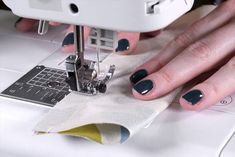 a woman is using a sewing machine to sew on her nail polishes,