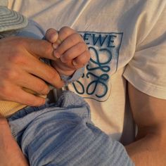 a close up of a person holding a baby in his lap and wearing a hat