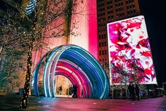 an outdoor display in front of a large building with colorful lights on it's sides