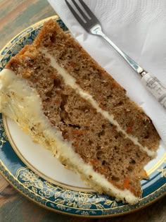 a piece of carrot cake on a plate with a fork and napkin next to it