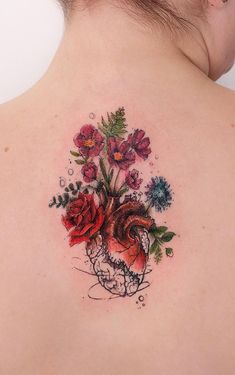 a woman's back tattoo with flowers on it