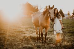 a woman standing next to a horse in a field