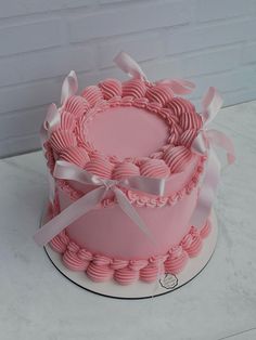 a pink cake with white ribbons and bows