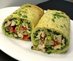 a burrito cut in half on a plate with lettuce, tomato and chicken