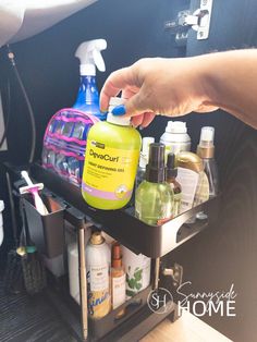 Woman pulls hair care product from sliding tray after organizing bathroom cabinet.