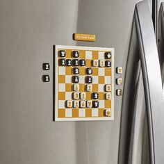 a checkerboard magnet on the side of a stainless steel refrigerator with it's door open