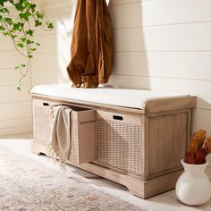 a wooden bench with two baskets underneath it and a coat rack on the wall next to it