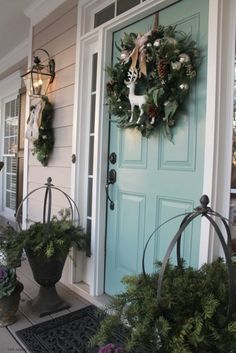 the front door is decorated with wreaths and potted plants